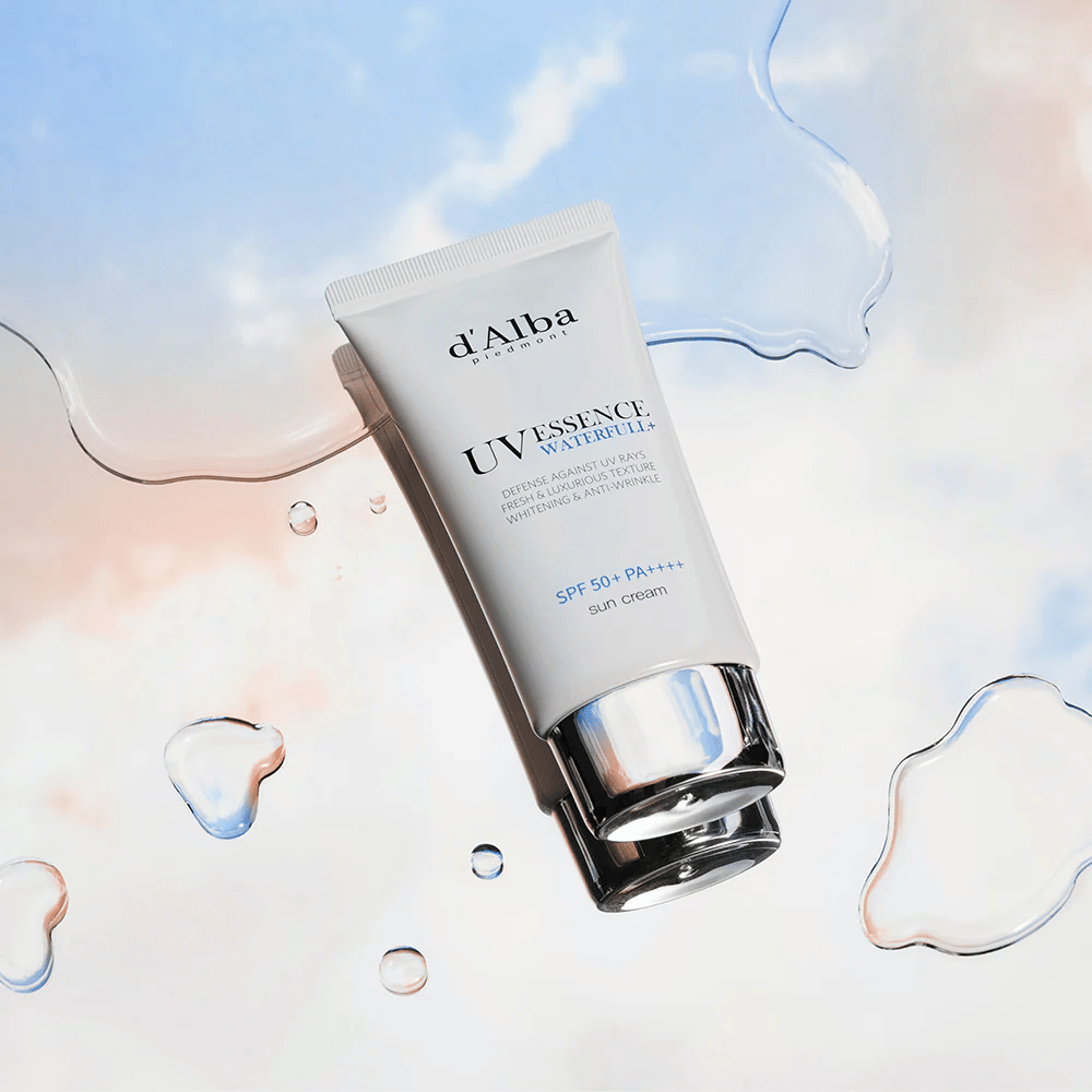 Productafbeelding van d'Alba UV Essence Waterfull+ Sun Cream met SPF 50+ PA++++, geplaatst tegen een achtergrond met waterspatten en een blauwroze hemel - symboliseert lichte en hydraterende zonbescherming.