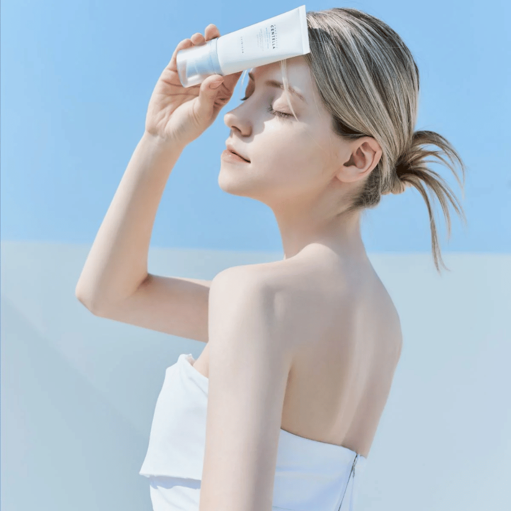 Een vrouw brengt SKIN1004 Madagascar Centella Hyalu-Cica Water-Fit Sun Serum 50ml aan om haar gezicht te beschermen tegen UV-stralen.