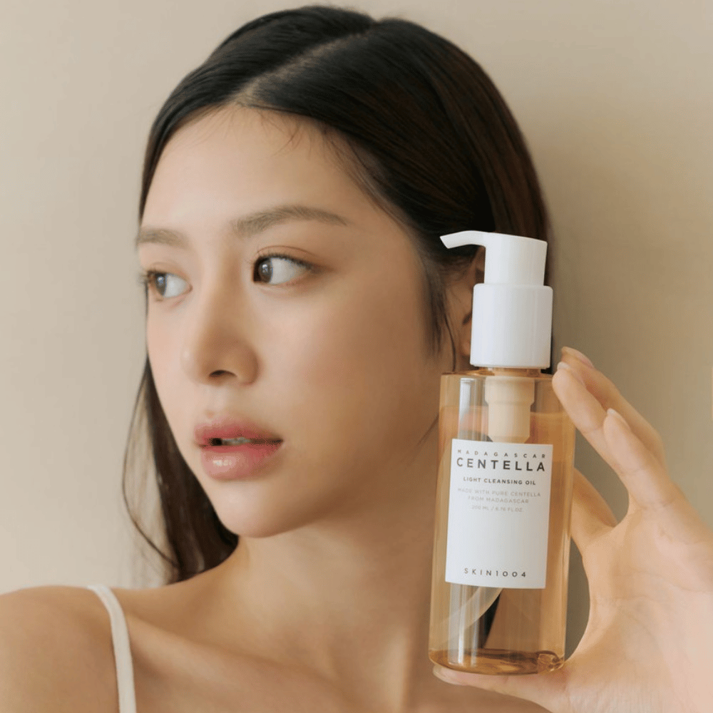 Een vrouw die een fles SKIN1004 Madagascar Centella Light Cleansing Oil 200 ml gezichtsreiniger omhoog houdt.
