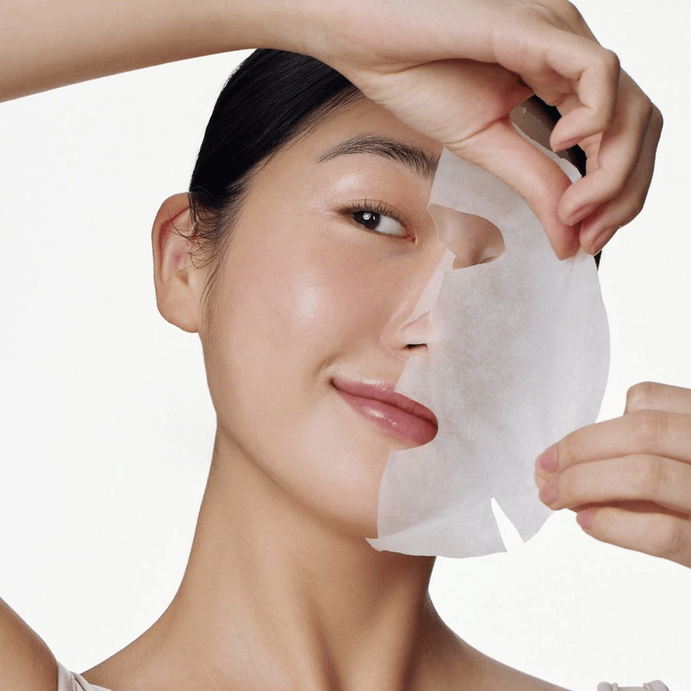 Deze afbeelding toont een persoon die een gezichtsmasker gebruikt, specifiek "Galactomyces Glutathione Daily Mask" van Some By Mi. Het masker verheldert de huid en geeft een stralende glans, terwijl het de huid verzorgt en diep hydrateert, dankzij ingrediënten zoals glutathion en vitamine C.