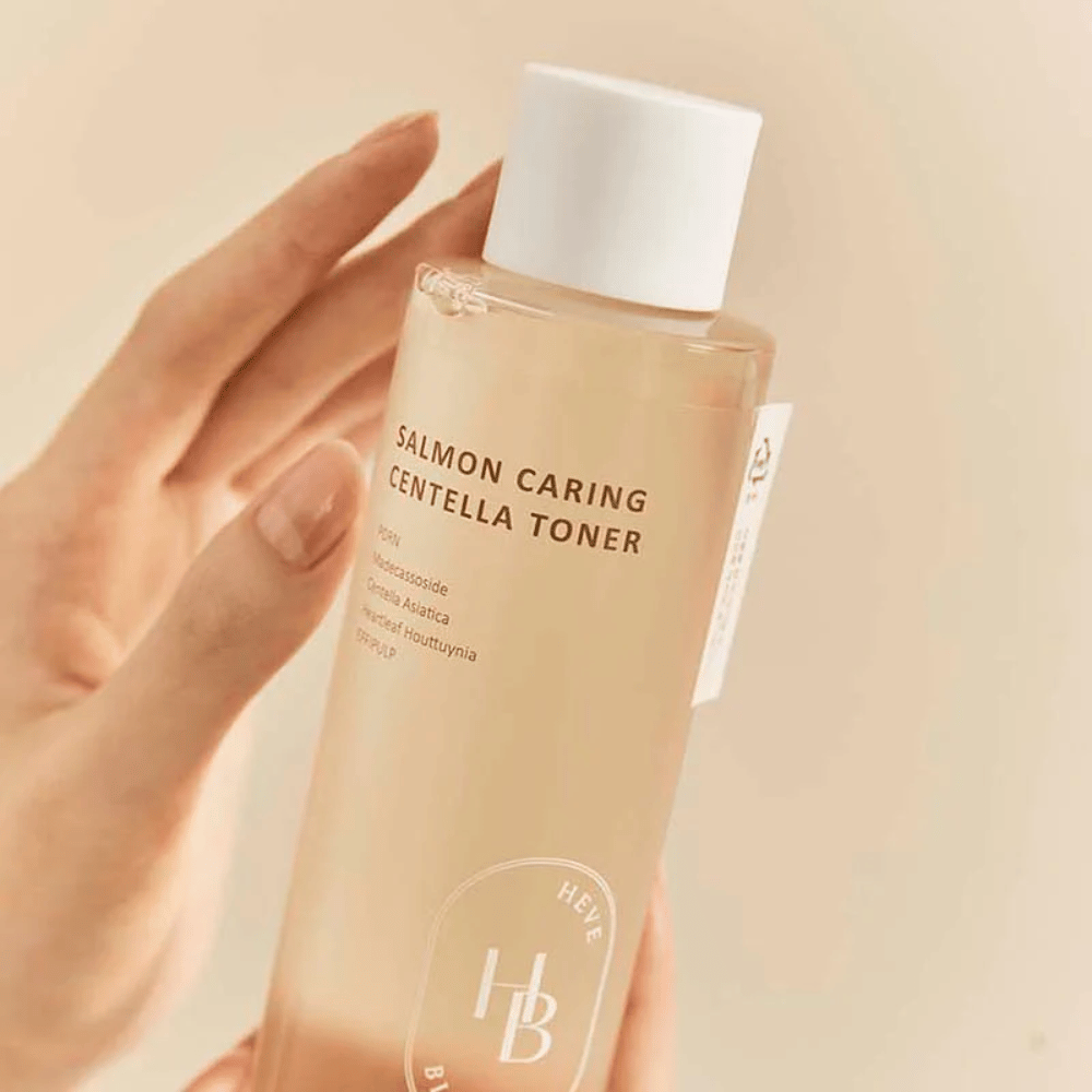 Close-up van Salmon Caring Centella Toner in de hand – kalmerende toner met PDRN en plantextracten die helpen de huid te versterken en het gevoel van irritatie te verminderen.