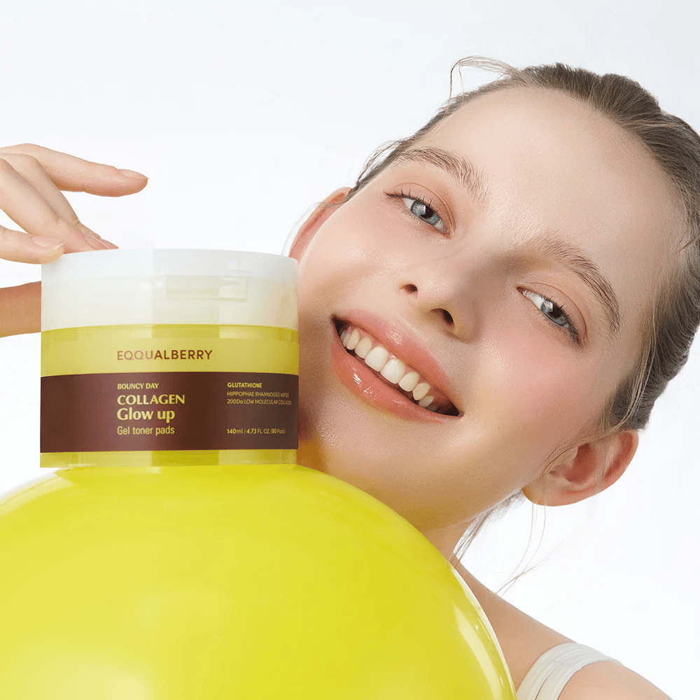 Glimlachende model die Bouncy Day Collagen Glow up Gel Toner Pads vasthoudt, die helpt om een jeugdige gloed en stevigheid te geven met laagmoleculair collageen en glutathion.