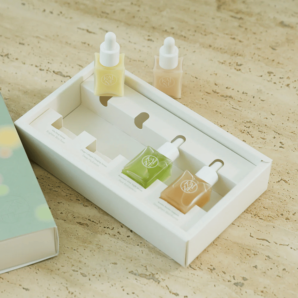 Vier kleurrijke serumflessen van KAINE Serum Discovery Kit met pipetdop, ontworpen om aan verschillende huidbehoeften te voldoen in een minimalistische en stijlvolle verpakking.