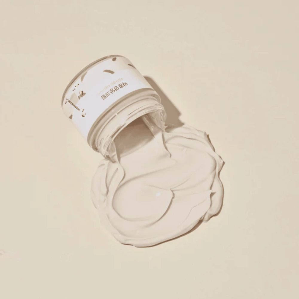 Mixsoon Soybean Nourishing Cream gemorst uit de pot op een beige achtergrond. De rijke textuur van de crème toont zijn intens hydraterende eigenschappen.