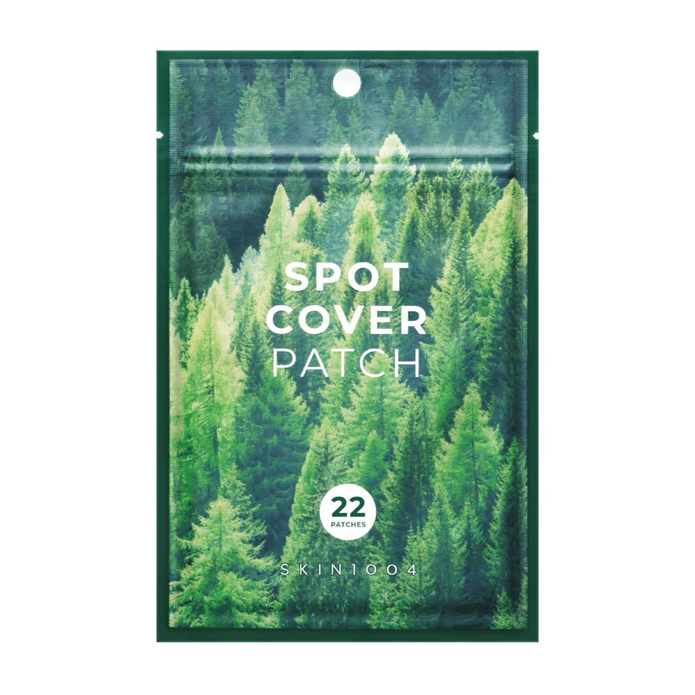 Verpakking met "Spot Cover Patch" die 22 pleisters bevat, ontworpen met een groen bosmotief. De tekst "SPOT COVER PATCH" is in het wit op de voorkant gedrukt, en een cirkel markeert het aantal pleisters. Het product is van het merk SKIN1004.