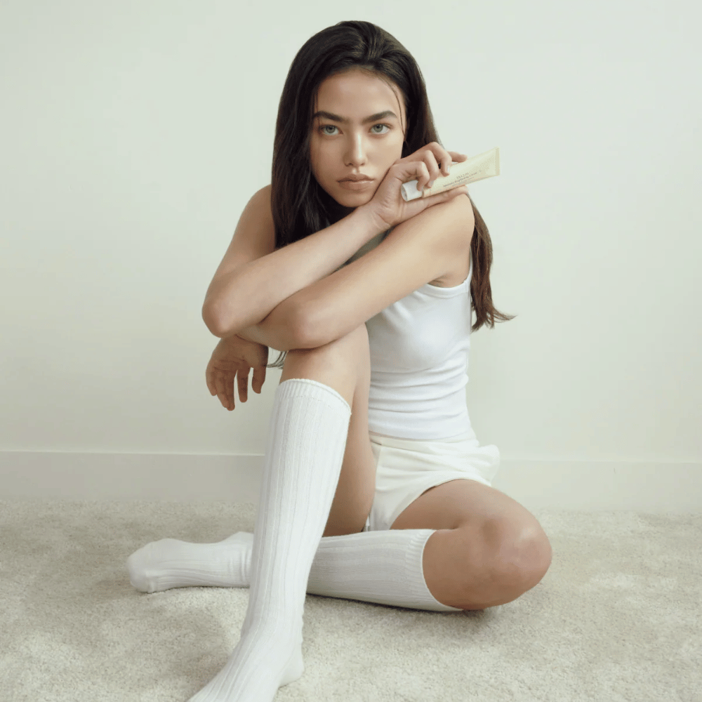 Lifestylebeeld met model dat het product vasthoudt in een lichte en minimalistische omgeving. De afbeelding straalt een zuiver, natuurlijk en rustig huidverzorgingsgevoel uit, gekoppeld aan glow en een brightening-effect.