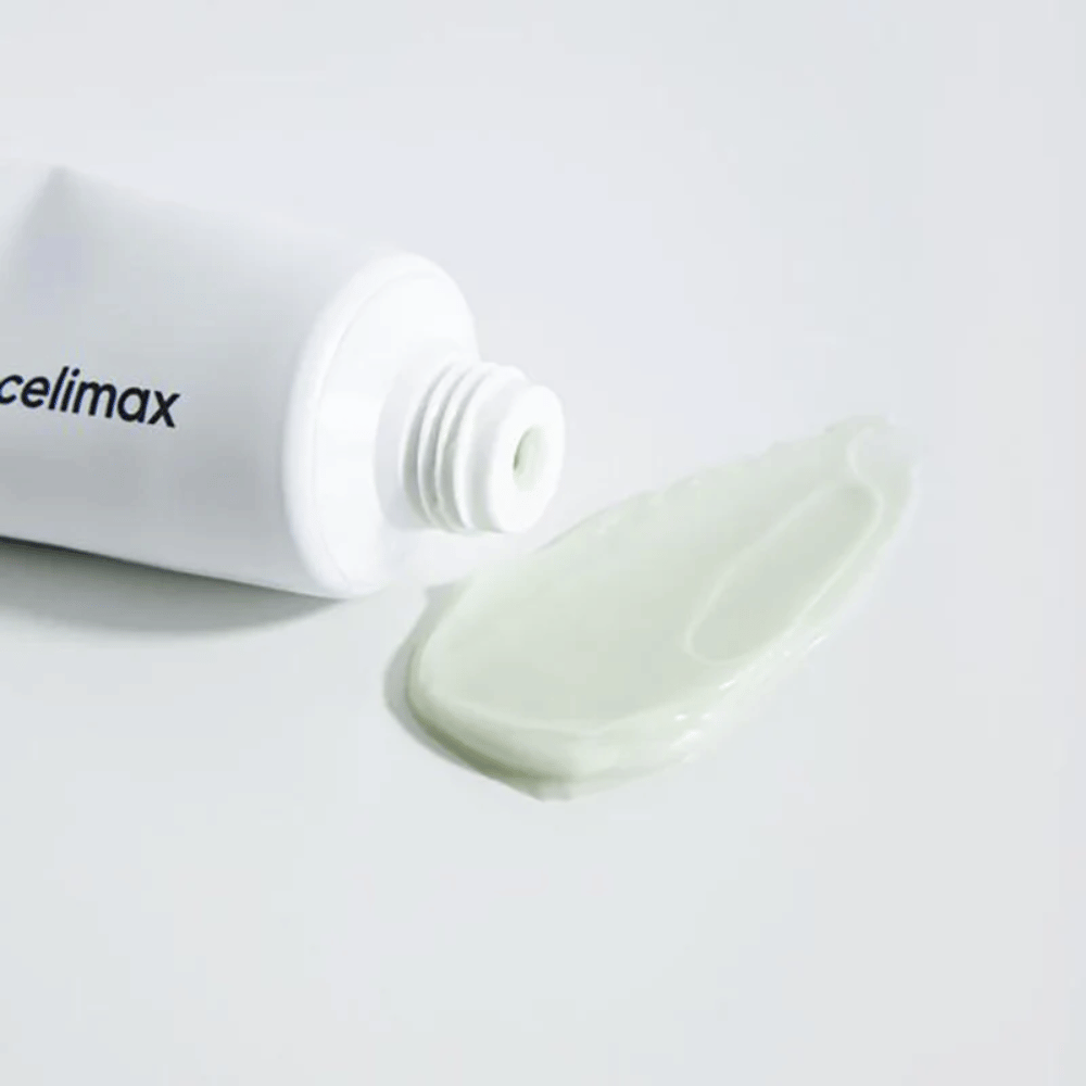 Celimax Noni Energy Repair Cream in een witte tube met een kleine hoeveelheid lichtgroene crème die naast de tube op een witte ondergrond is gespoten. De crème is bedoeld om de huid te voeden en te herstellen.