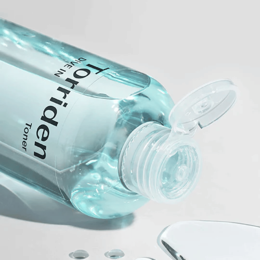 Een fles DIVE-IN Low Molecule Hyaluronic Acid Toner 300ml naast een glas water, bevordert Torriden en hydratatie.
