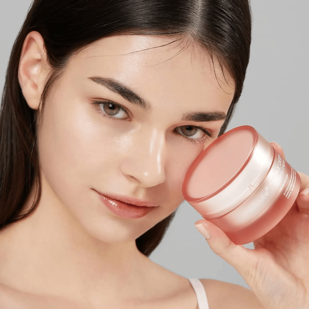De afbeelding toont een vrouw die een pot met Triple Collagen Cream vasthoudt. De crème is ontworpen om de elasticiteit en hydratatie van de huid te verbeteren. De huid van de vrouw ziet er glad en goed verzorgd uit.




