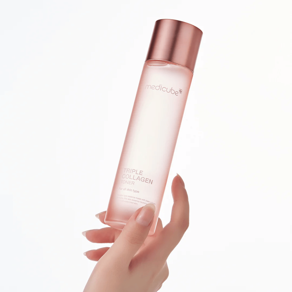 Hand die een roze fles van Medicube Triple Collagen Toner 4.0 vasthoudt, een hydraterende en verstevigende toner voor alle huidtypes.