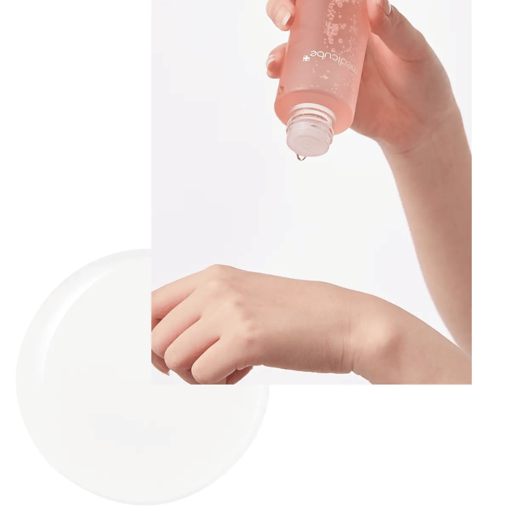 Hand die Medicube Triple Collagen Toner 4.0 uit een roze fles op de huid aanbrengt, toont de hydraterende consistentie.