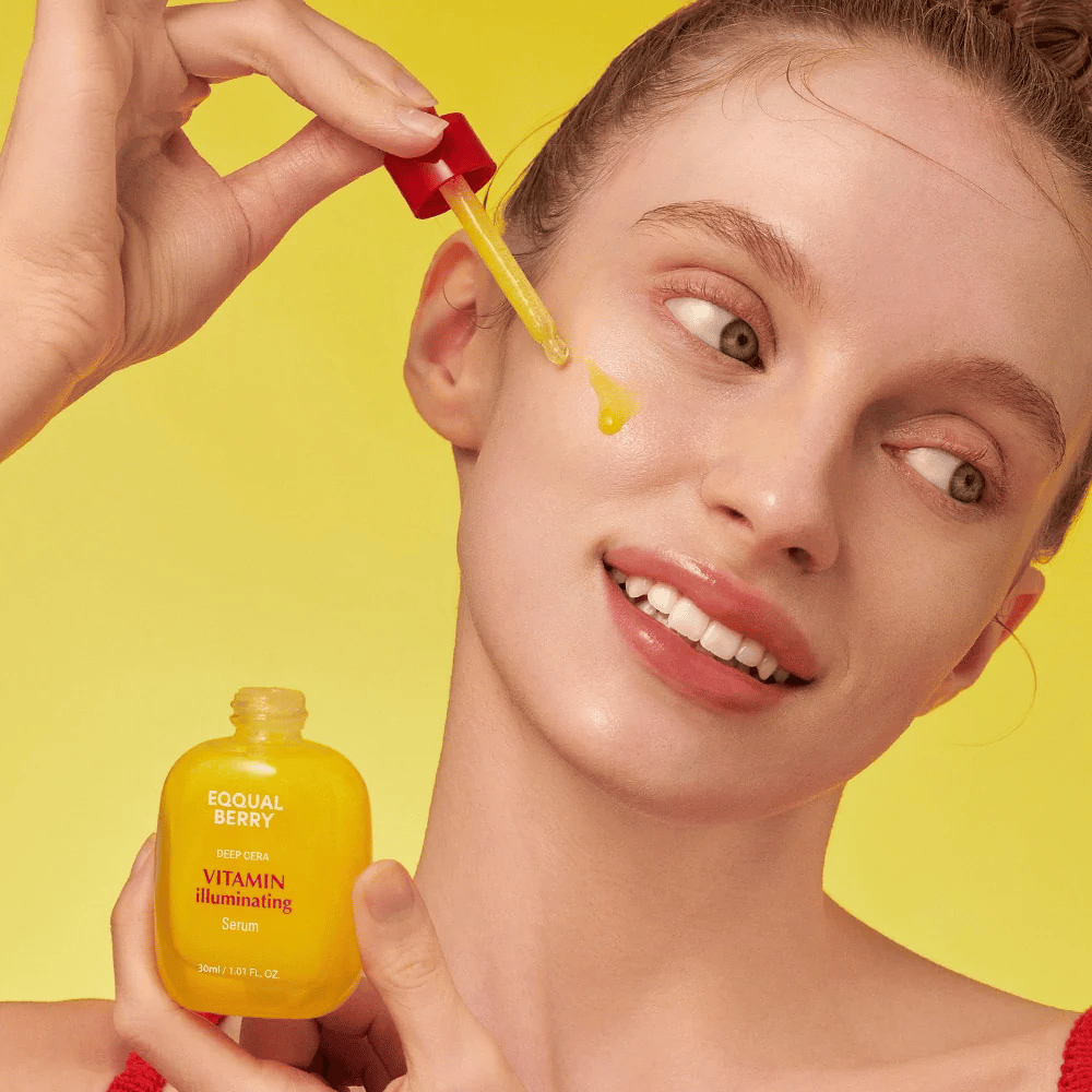 Lachende vrouw brengt Equal Berry Vitamin Illuminating Serum aan met een pipet. Frisse en stralende huid tegen een levendige gele achtergrond die bij de kleur van het serum past.