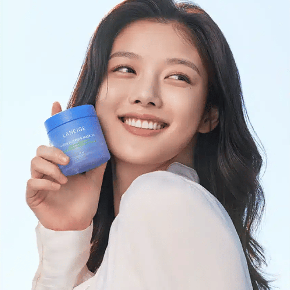 Lachende vrouw houdt een blauwe pot van LANEIGE Water Sleeping Mask omhoog voor een lichtblauwe achtergrond.