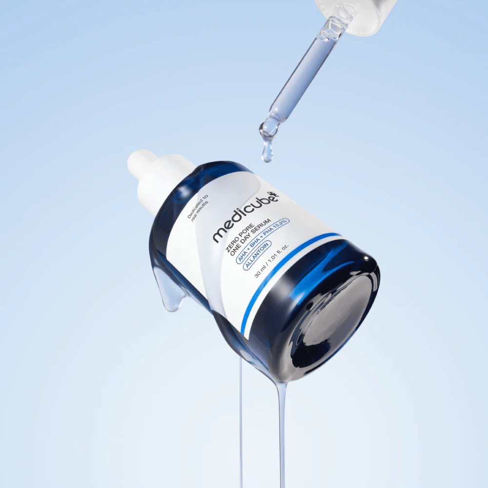 Fles van Medicube Zero Pore One Day Serum met pipet en druppelende serumdruppels tegen een lichtblauwe achtergrond.