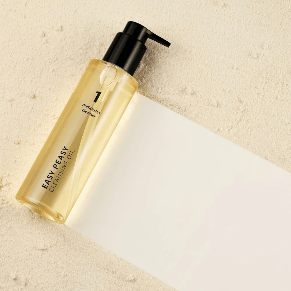 Numbuzin No.1 Easy Peasy Cleansing Oil liggend op zandkleurig oppervlak met schaduw.