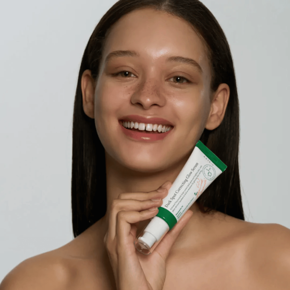 Een jonge vrouw houdt een tube van AXIS - Y Dark Spot Correcting Glow Serum 50ml vast.