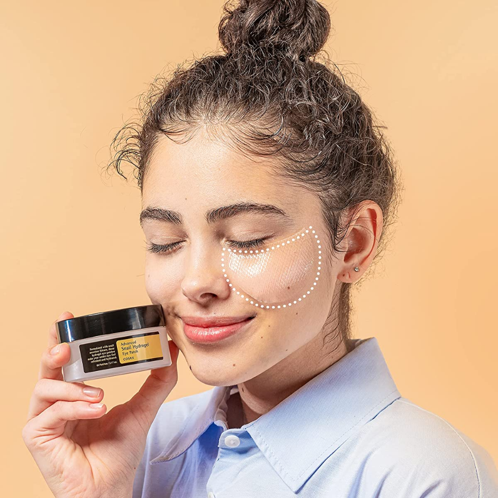 Een vrouw die een pot COSRX Advanced Snail Hydrogel Eye Patch 60 st gezichtscrème vasthoudt.