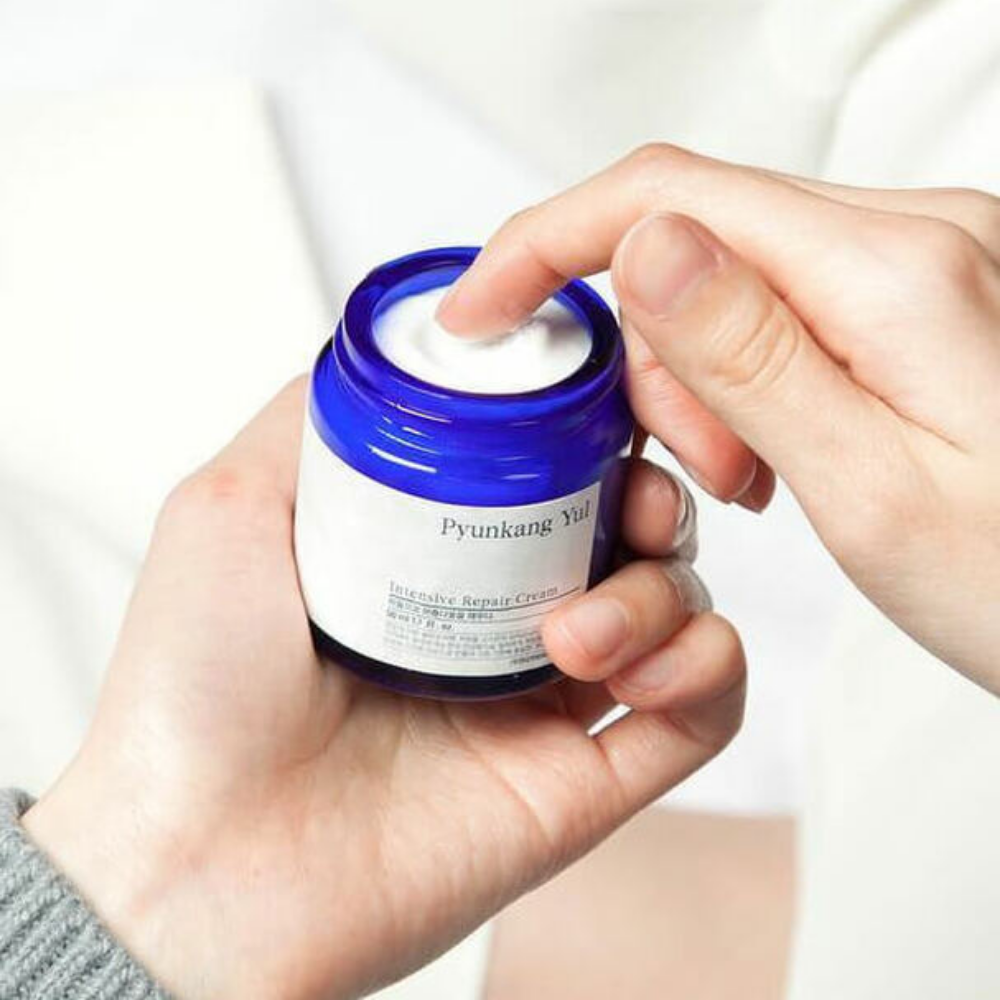 Een persoon houdt een pot Pyunkang Yul Intensive Repair Cream 50ml vast.