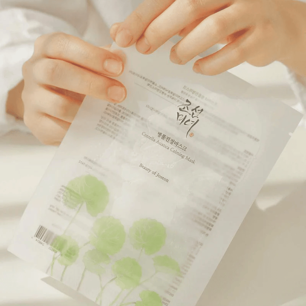 Een persoon die een vel papier omhooghoudt met een Beauty of Joseon Centella Asiatica Calming Mask 1 st erop.