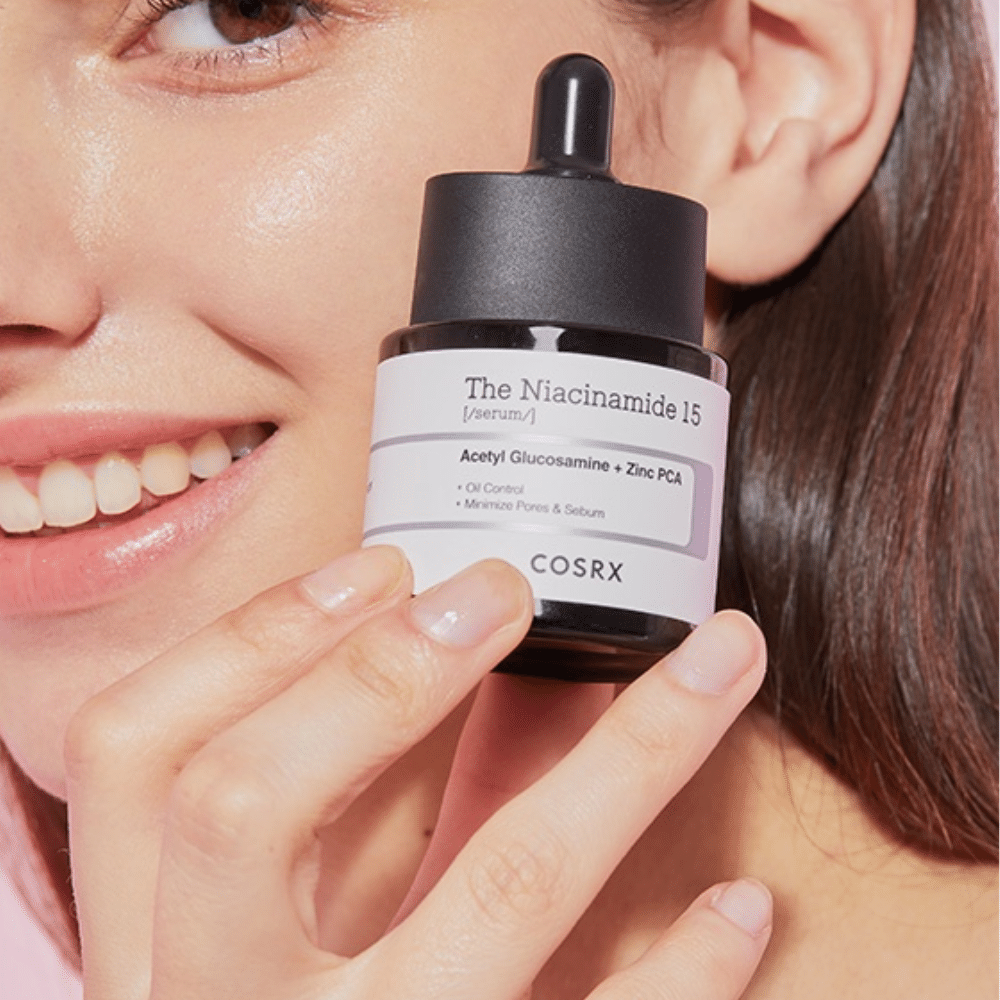 Een vrouw houdt een flesje COSRX Niacinamide 15 Serum 20ml vast voor niacinamide en talgproductie.