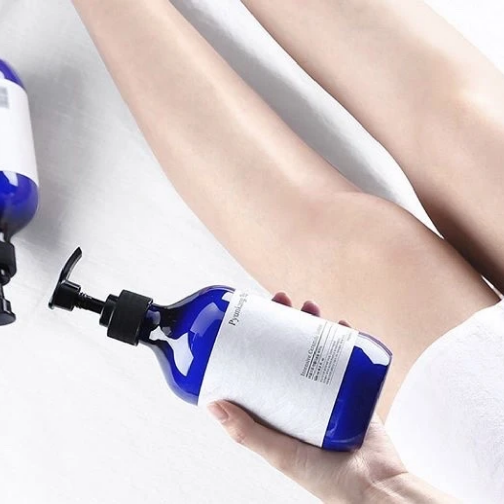 Een vrouw die een fles Pyunkang Yul Intensive Ceramide Lotion 500ml naast haar benen houdt.
