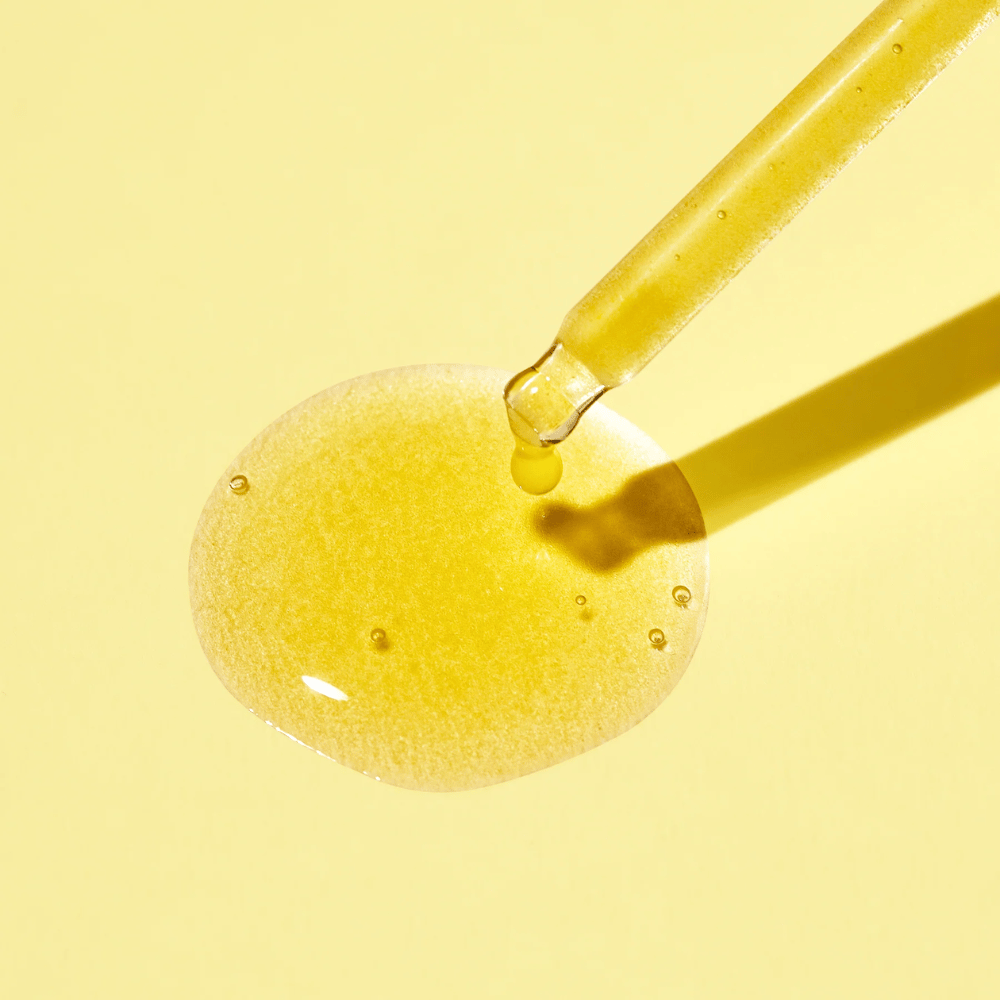 Een druppel vloeistof op een gele achtergrond, met MISSHAs Vita C Plus Spot Correcting & Firming Ampoule.