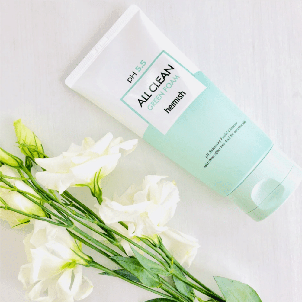 Een tube heimish All Clean Green Foam 150ml naast witte bloemen.